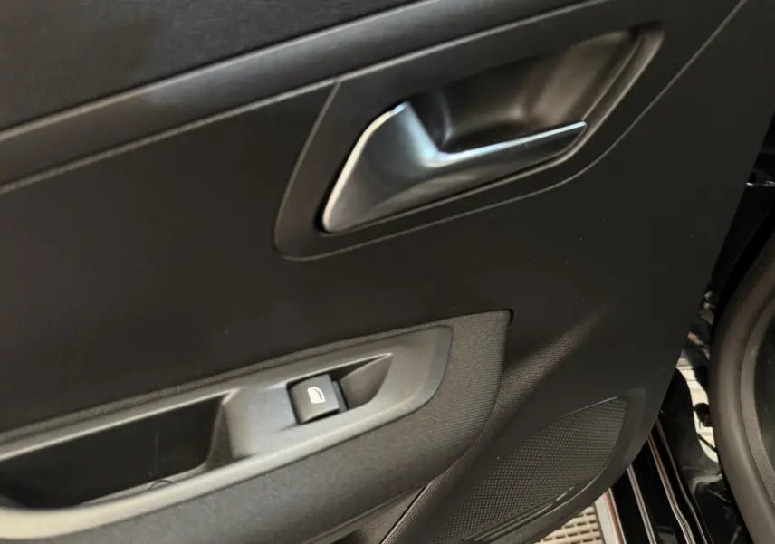 Gros plan sur la porte avant gauche noire du Peugeot 208 2021, montrant la poignée et le bouton de lève-vitre.
