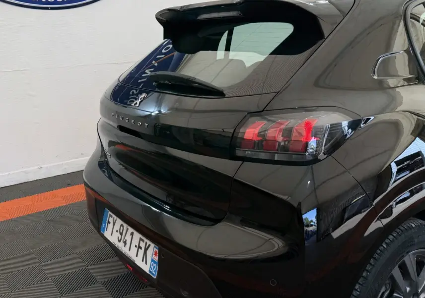 Vue 3/4 arrière droite d'une Peugeot 208 noire avec feux arrière LED et lunette arrière surélevée.