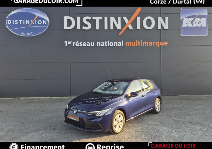 Volkswagen Golf bleu vue 3/4 avant droit, avec phares LED et jantes alliage visibles, stationnée devant un mur gris.