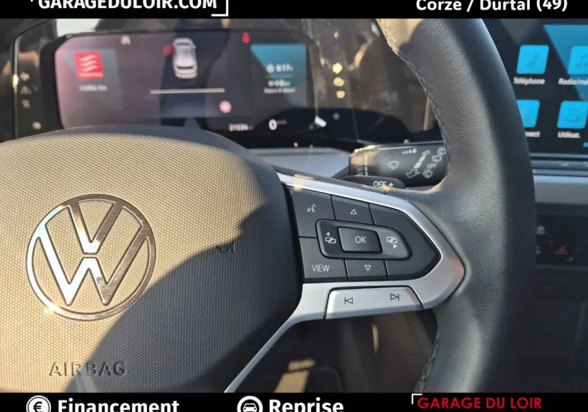 Gros plan sur le volant noir de la Volkswagen Golf 2023 avec commandes multifonctions et logo VW central.