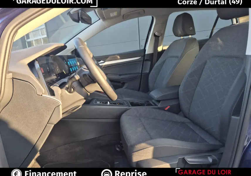 Vue intérieure côté conducteur de la Volkswagen Golf 2023 bleu, avec sièges tissu gris et tableau de bord digital.