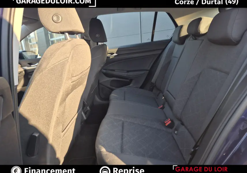 Vue intérieure côté droit des sièges arrière gris foncé d'une Volkswagen Golf 2023 bleue, avec appuie-têtes et ceintures visibles.