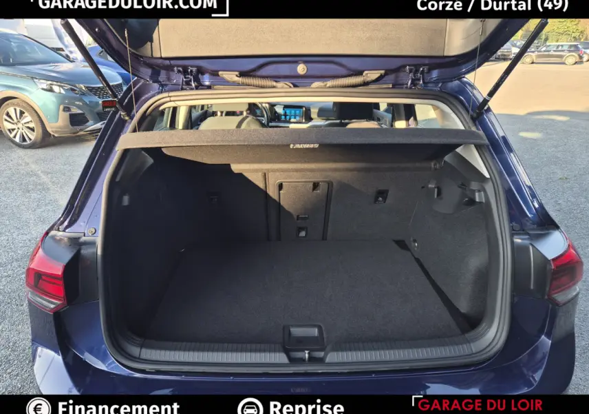 Vue arrière ouverte sur le coffre spacieux d'une Volkswagen Golf 2023 bleu, avec tablette cache-bagages relevée.