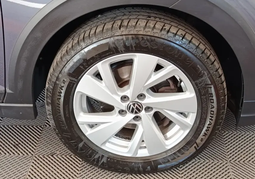 Gros plan sur la roue avant gauche du Volkswagen Taigo gris foncé avec jante alliage et pneu Firestone Roadhawk.