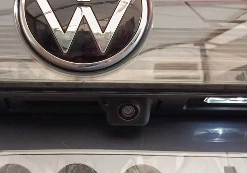 Gros plan sur la caméra de recul sous le logo Volkswagen d’un Taigo gris foncé 2023.