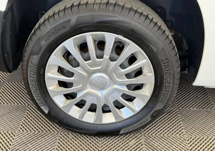 Gros plan sur la roue avant droite d’un Toyota Proace City blanc, jante acier avec enjoliveur gris.