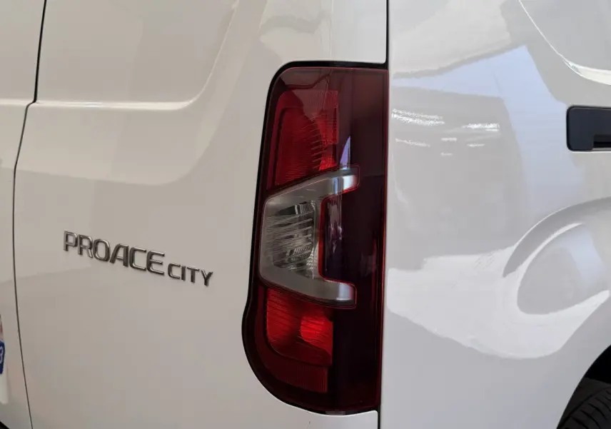 Gros plan sur le feu arrière droit et le logo PROACE CITY d’un utilitaire Toyota blanc.