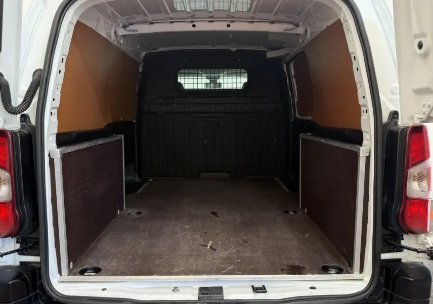 Vue arrière du coffre blanc du Toyota Proace City 1.5 LONG 130 D-4D Business, montrant l’espace de chargement vide et cloison pleine.