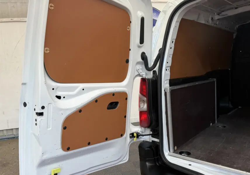 Vue arrière ouverte du Toyota Proace City blanc, montrant l'intérieur utilitaire avec panneaux de protection marron.