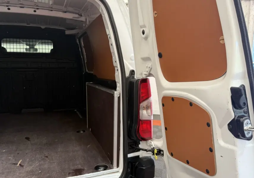 Vue arrière ouverte du Toyota Proace City blanc, montrant l'intérieur de la zone de chargement avec panneaux de protection marron.