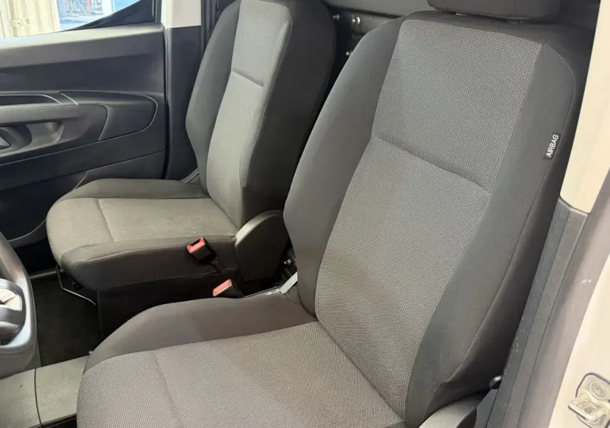 Vue intérieure rapprochée des sièges avant gris foncé du Toyota Proace City 1.5 Long 130 D-4D Business, porte ouverte côté droit.