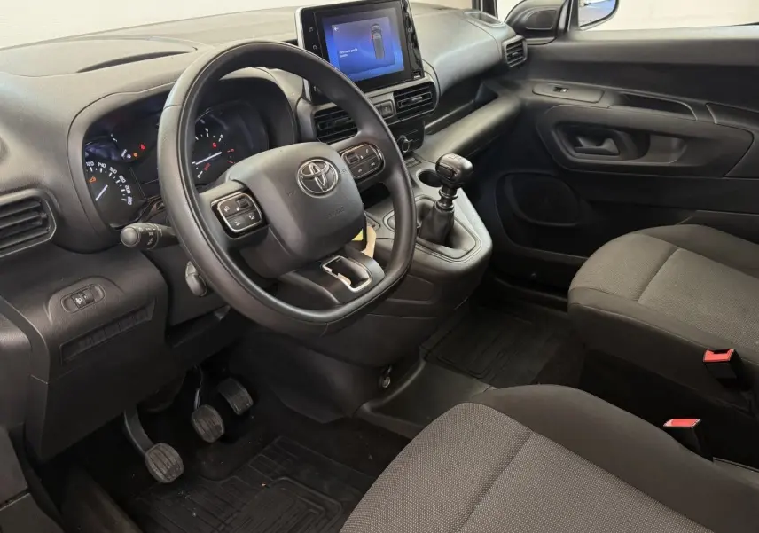 Vue intérieure côté conducteur du Toyota Proace City 2022, volant multifonctions, écran tactile central et boîte manuelle noire.