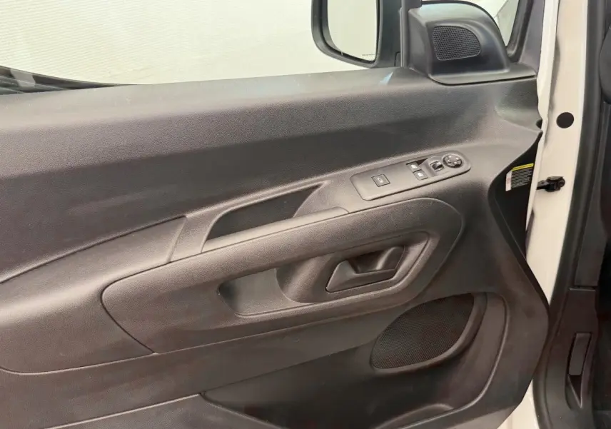 Vue rapprochée de la porte avant droite noire du Toyota Proace City blanc, avec commandes électriques des vitres et rétroviseurs.