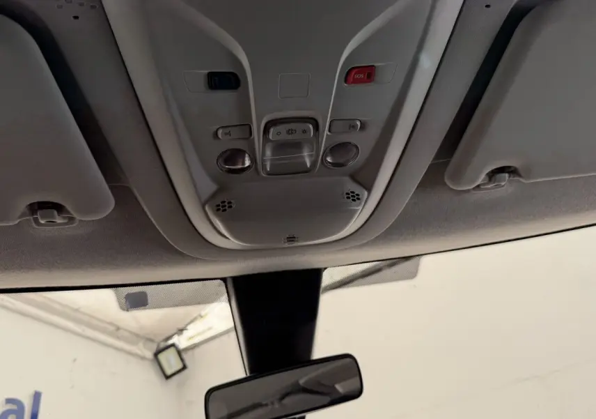 Vue intérieure du toit avec commandes d'éclairage, bouton SOS rouge et rétroviseur central du Toyota Proace City blanc.