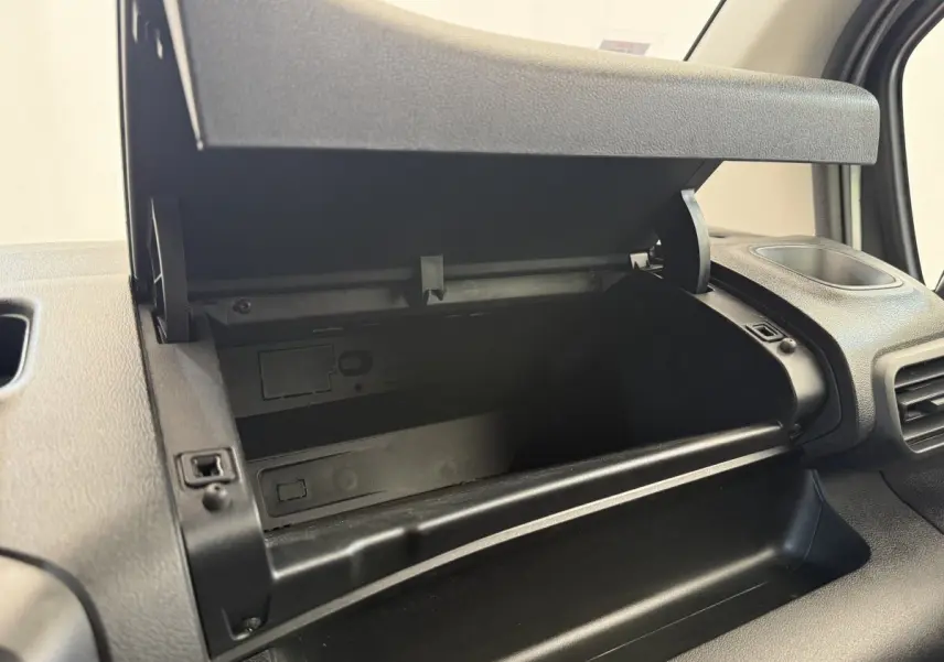 Vue rapprochée de la boîte à gants ouverte côté passager dans l'habitacle noir du Toyota Proace City blanc.