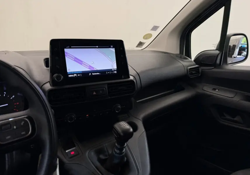 Vue intérieure côté passager du tableau de bord noir du Toyota Proace City avec écran tactile et levier de vitesses manuel.