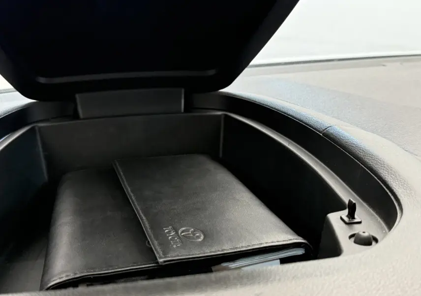Coffre de rangement ouvert sur le tableau de bord d’un Toyota Proace City blanc, avec un porte-documents noir à l’intérieur.