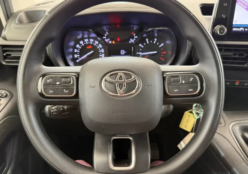 Vue rapprochée du volant multifonctions noir de la Toyota Proace City 2022 avec tableau de bord et écran tactile visible à droite.