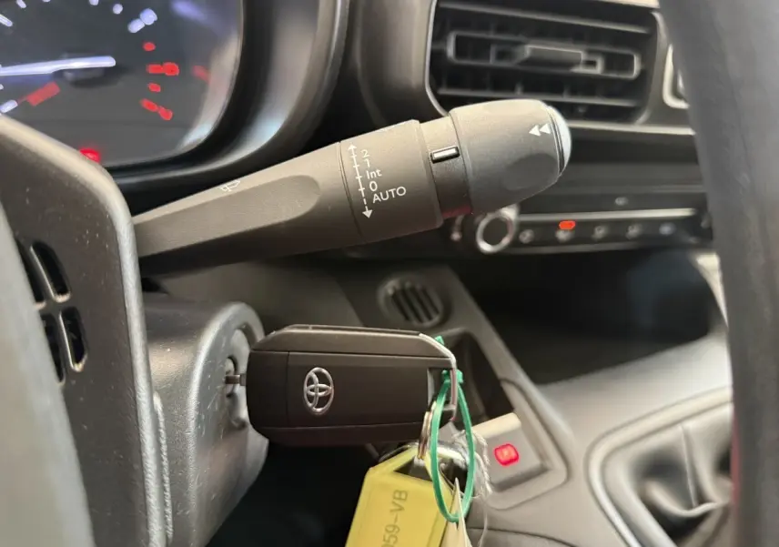 Gros plan intérieur sur la clé Toyota insérée dans le contact, avec commande d’essuie-glace et partie du tableau de bord visible.