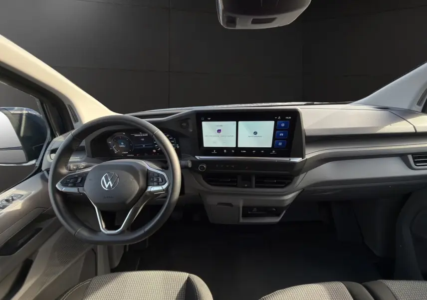 Vue intérieure du tableau de bord du Volkswagen Transporter 2025, avec volant multifonctions et écran tactile central large.