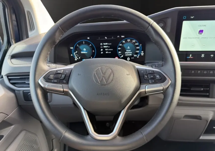 Vue intérieure centrée sur le volant noir du Volkswagen Transporter 2025 avec tableau de bord digital et écran tactile.