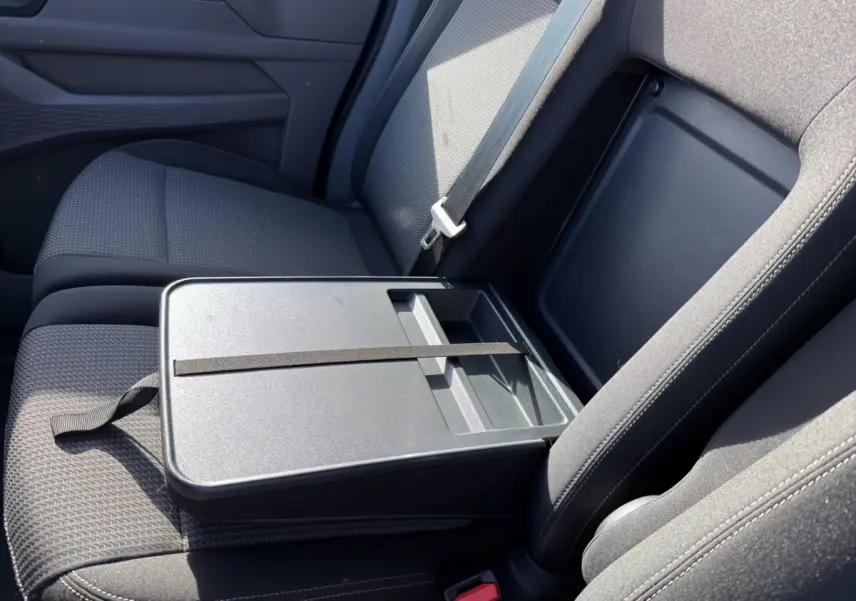 Vue rapprochée de l'intérieur côté passager du Volkswagen Transporter 2025, siège gris avec tablette repliable.