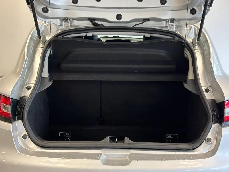 Coffre ouvert vu de l'arrière d'une Renault Clio gris platine, montrant l'espace de chargement et la tablette cache-bagages.