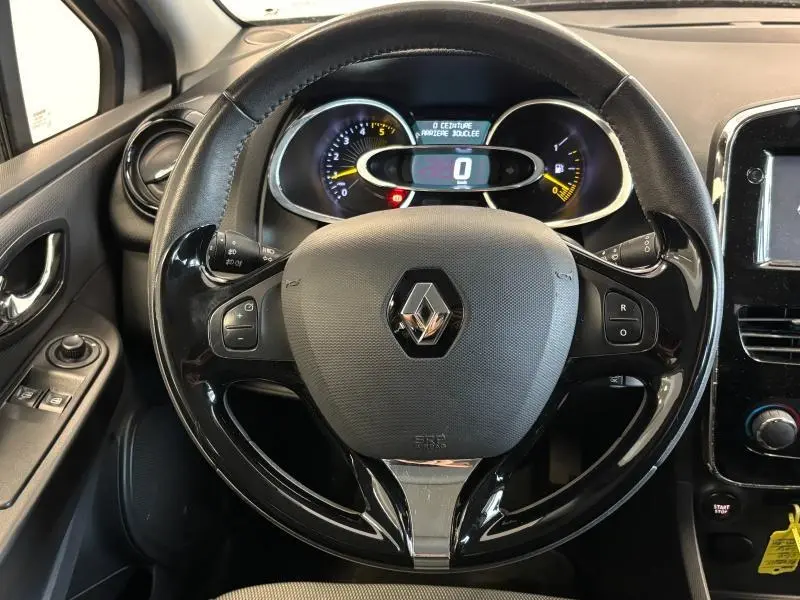 Volant cuir noir avec commandes audio et tableau de bord éclairé d'une Renault Clio 1.5 dCi gris platine, vue de face intérieure.
