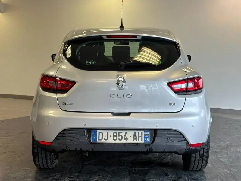 Vue arrière d'une Renault Clio gris platine de 2014 avec feux arrière allumés et plaque d'immatriculation française.