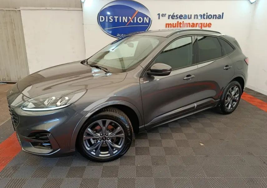 Ford Kuga gris clair en vue 3/4 avant droit, avec jantes alliage et toit noir dans un showroom intérieur.