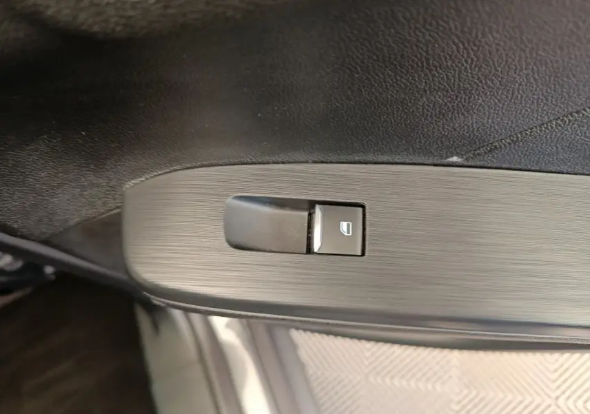 Bouton de commande de lève-vitre côté conducteur sur panneau de porte intérieur noir du Ford Kuga gris clair 2024.