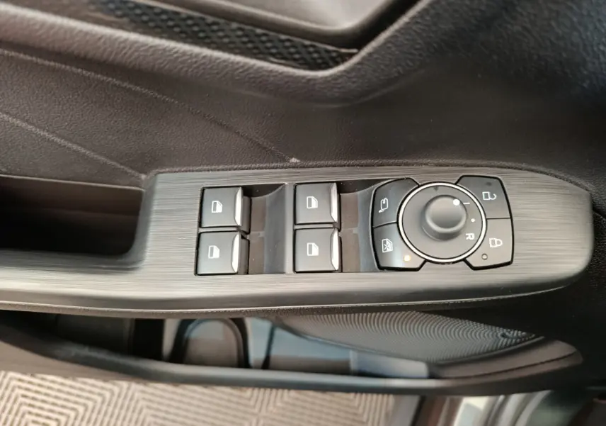 Gros plan sur les commandes de lève-vitres et rétroviseurs côté conducteur du Ford Kuga gris clair 2024.