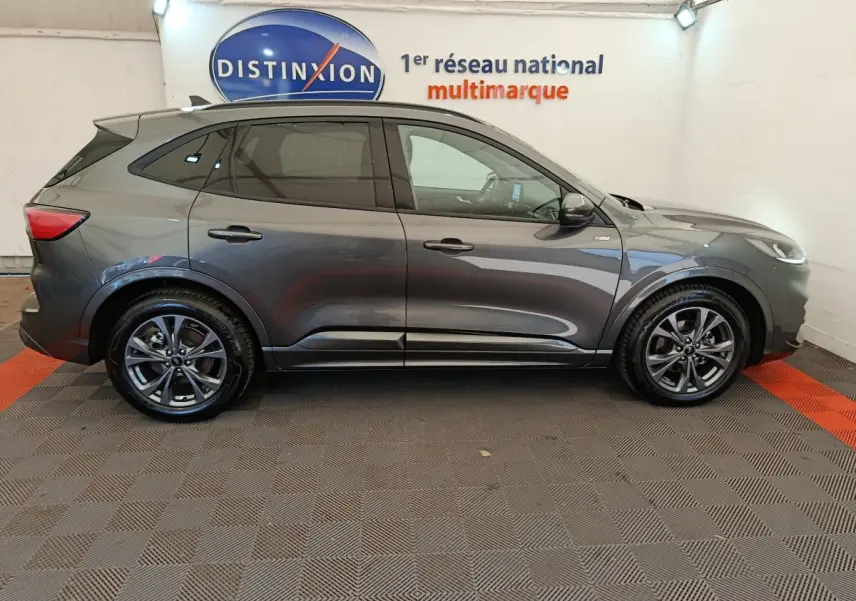 Ford Kuga 2024 gris clair vue de profil côté gauche dans un showroom avec jantes alliage et vitres teintées