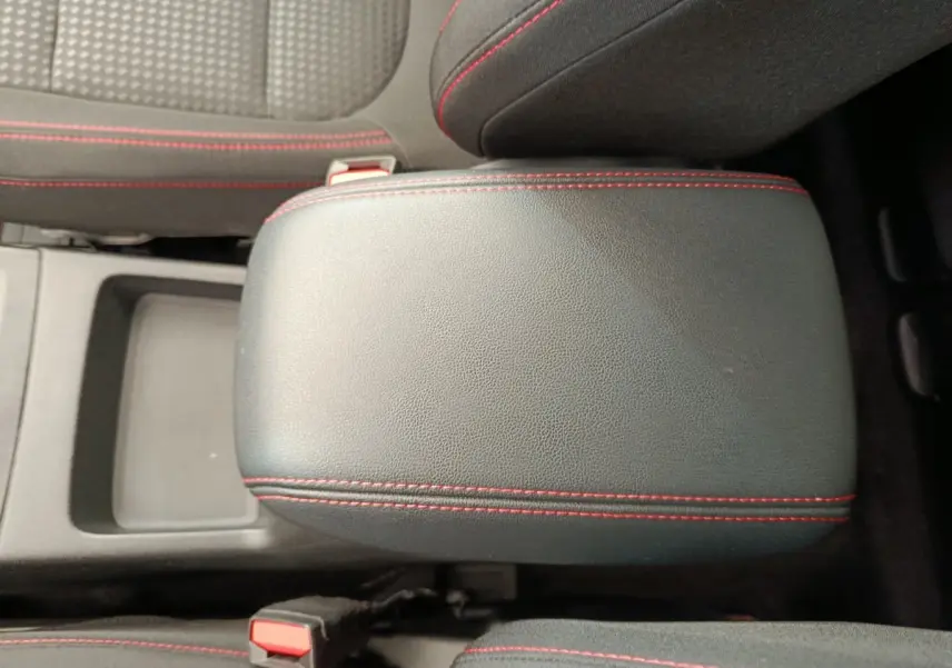 Accoudoir central noir avec surpiqûres rouges, entre les sièges avant du Ford Kuga 2024 St Line.