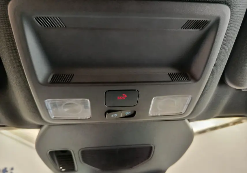 Vue en plongée sur le plafonnier noir du Ford Kuga 2024 avec bouton SOS rouge et éclairages intégrés.