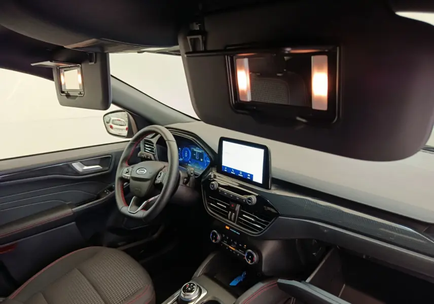 Intérieur du Ford Kuga 2024 St Line, vue côté conducteur, tableau de bord noir avec écran tactile et volant cuir.