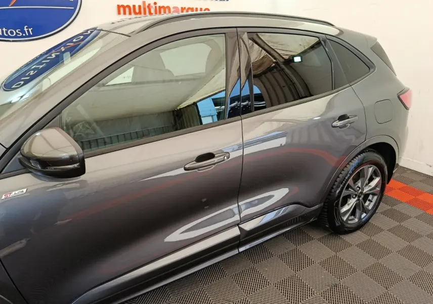 Vue latérale côté gauche d'un Ford Kuga gris clair finition ST Line avec jantes alliage et vitres teintées.