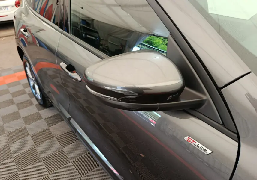 Rétroviseur côté gauche et badge ST Line sur la porte d'une Ford Kuga gris clair vue de profil avant.