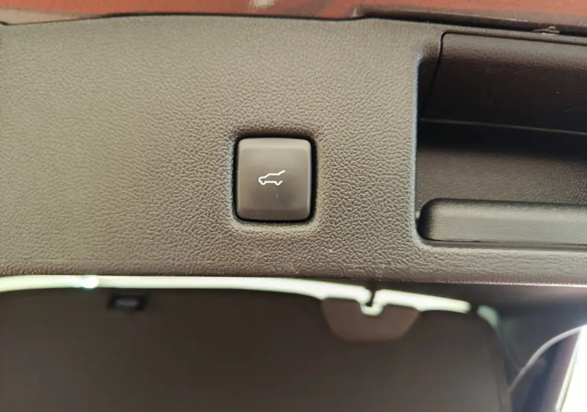 Bouton d'ouverture électrique du coffre sur la garniture intérieure du hayon du Ford Kuga gris clair 2024.