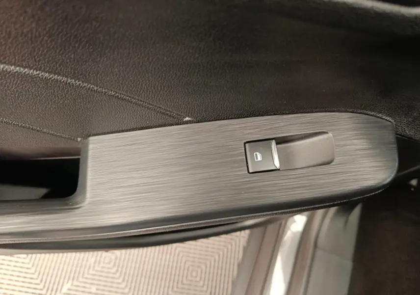 Gros plan sur la commande de lève-vitre côté gauche intérieur d'un Ford Kuga gris clair 2024 St Line.