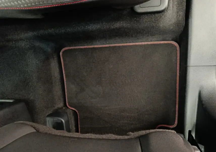 Tapis de sol noir avec surpiqûres rouges côté passager arrière du Ford Kuga gris clair 2024 St Line.