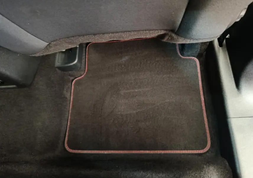Tapis de sol noir avec surpiqûres rouges sous le siège arrière côté droit du Ford Kuga gris clair 2024 St Line.