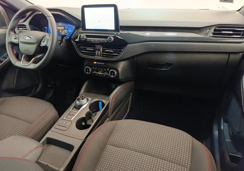 Intérieur avant du Ford Kuga 2024 gris clair, tableau de bord moderne avec écran tactile central et volant cuir noir.