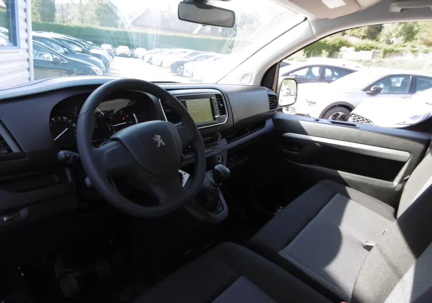 Intérieur du Peugeot Expert Long 2023, vue côté conducteur montrant le tableau de bord noir et la banquette tissu noir.