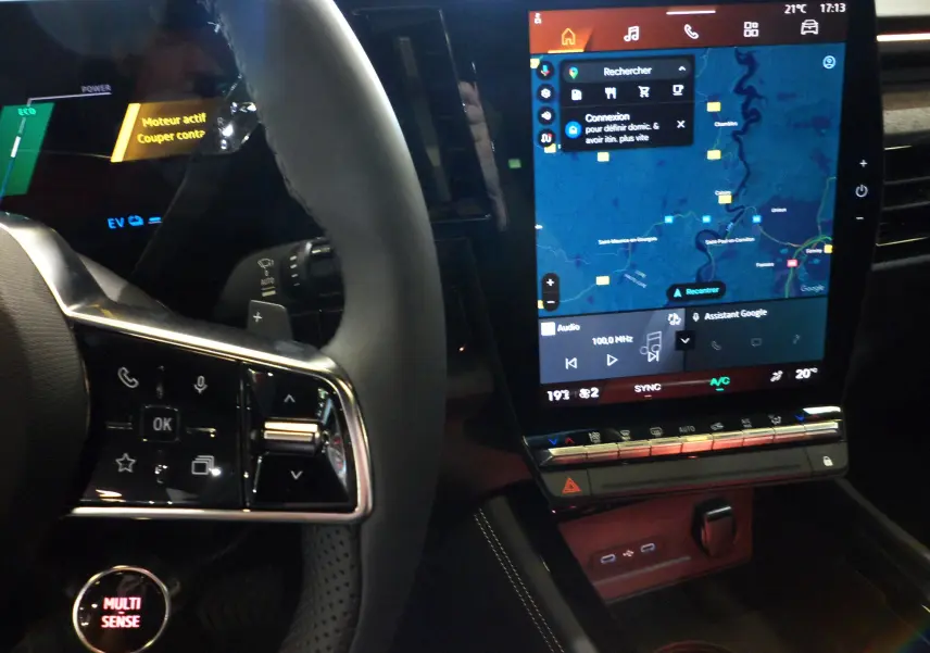 Vue rapprochée de l'intérieur du Renault Rafale E-Tech 2025, montrant le volant avec commandes et l'écran tactile central allumé.