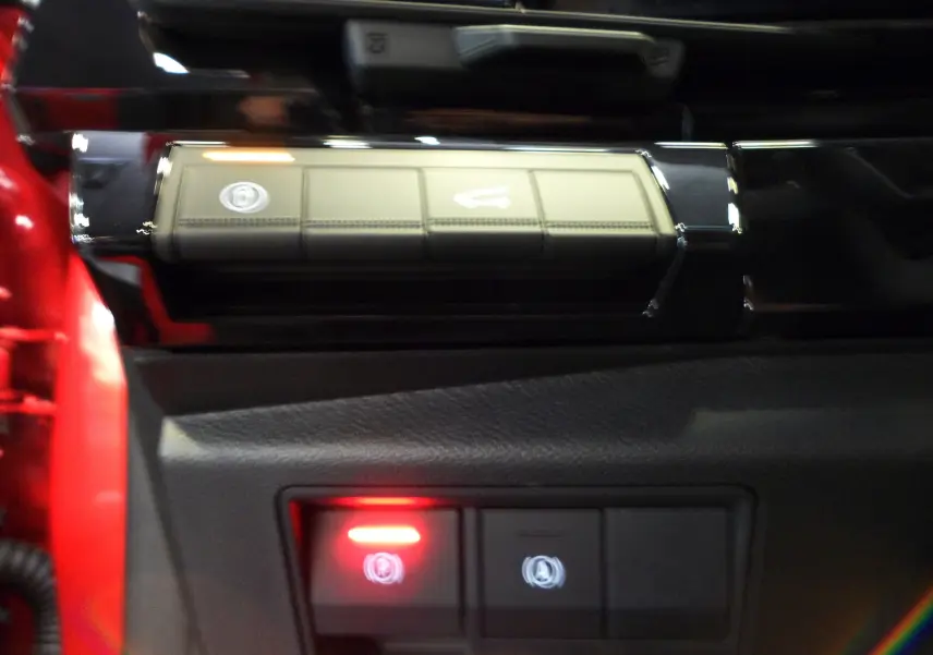 Gros plan sur les commandes intérieures du Renault Rafale rouge Flamme, avec bouton de frein à main électronique allumé.