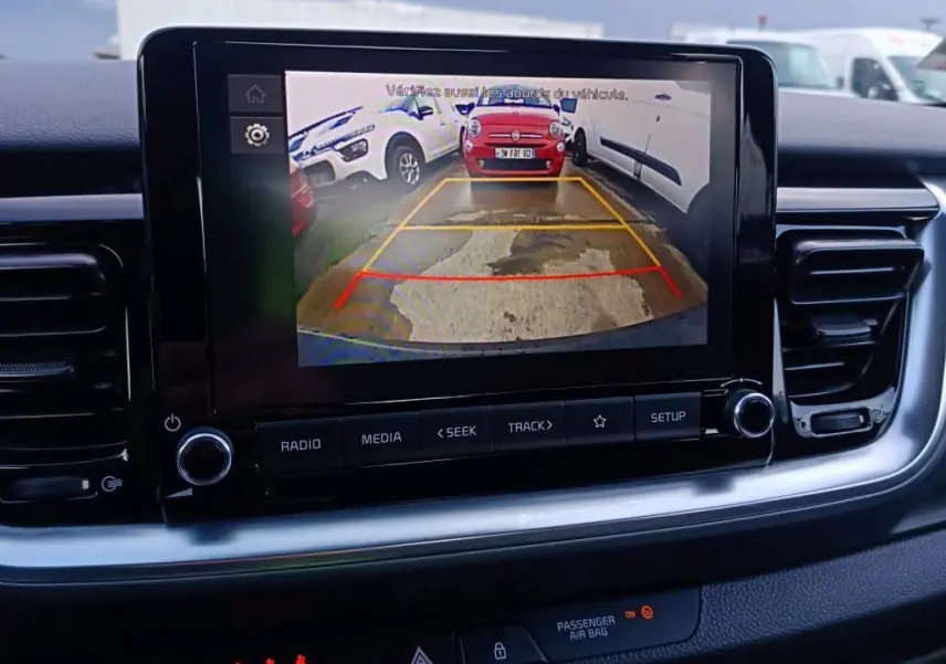 Écran central du Kia Stonic 2022 montrant la caméra de recul avec vue arrière et lignes de guidage colorées.