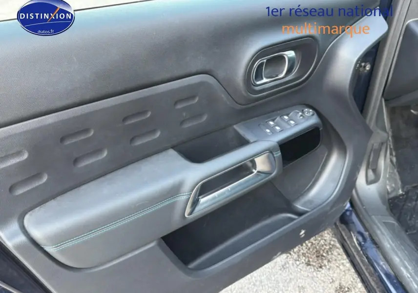 Vue rapprochée de la porte avant gauche du Citroën C5 Aircross bleu eclipse, montrant les commandes électriques et la poignée intérieure.