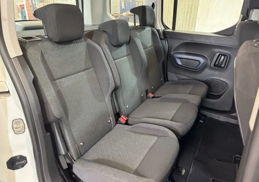 Vue intérieure des sièges arrière gris du Peugeot Rifter BlueHDi 100 Allure blanc, avec porte latérale ouverte.