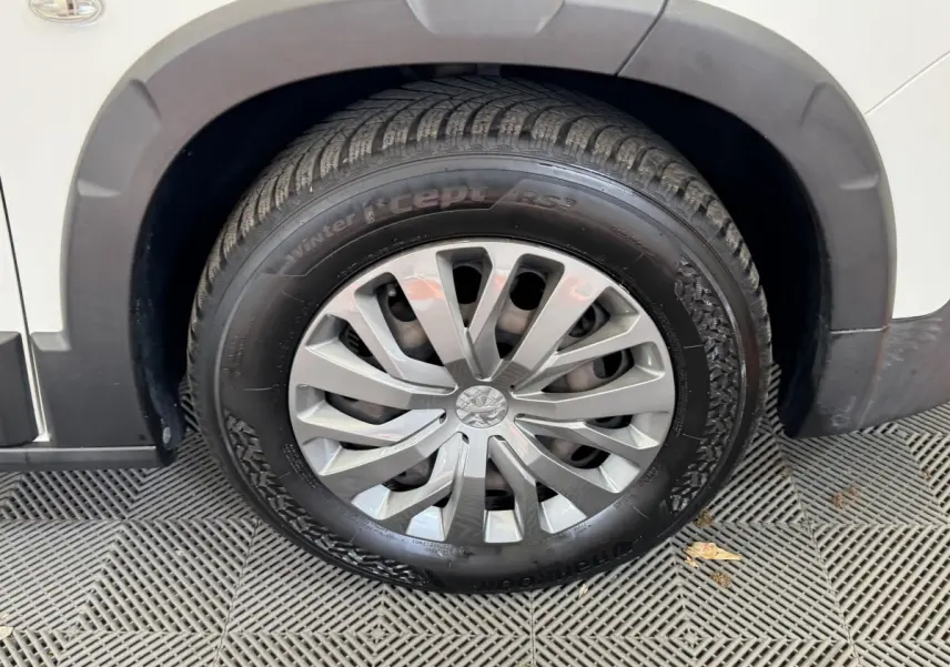 Gros plan sur la roue avant droite d’un Peugeot Rifter blanc, avec jante argentée et pneu hiver marqué "winter i*cept RS2".